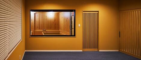 A hotel room with a large mirror reflecting a wooden interior, a sliding door, and a dark blue carpet.