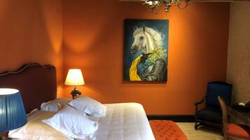 A bedroom with a bed, a lamp, a chair, and a painting on the wall.