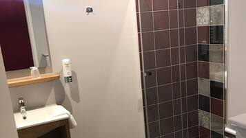 Een moderne badkamer met een douche, toilet en wastafel.