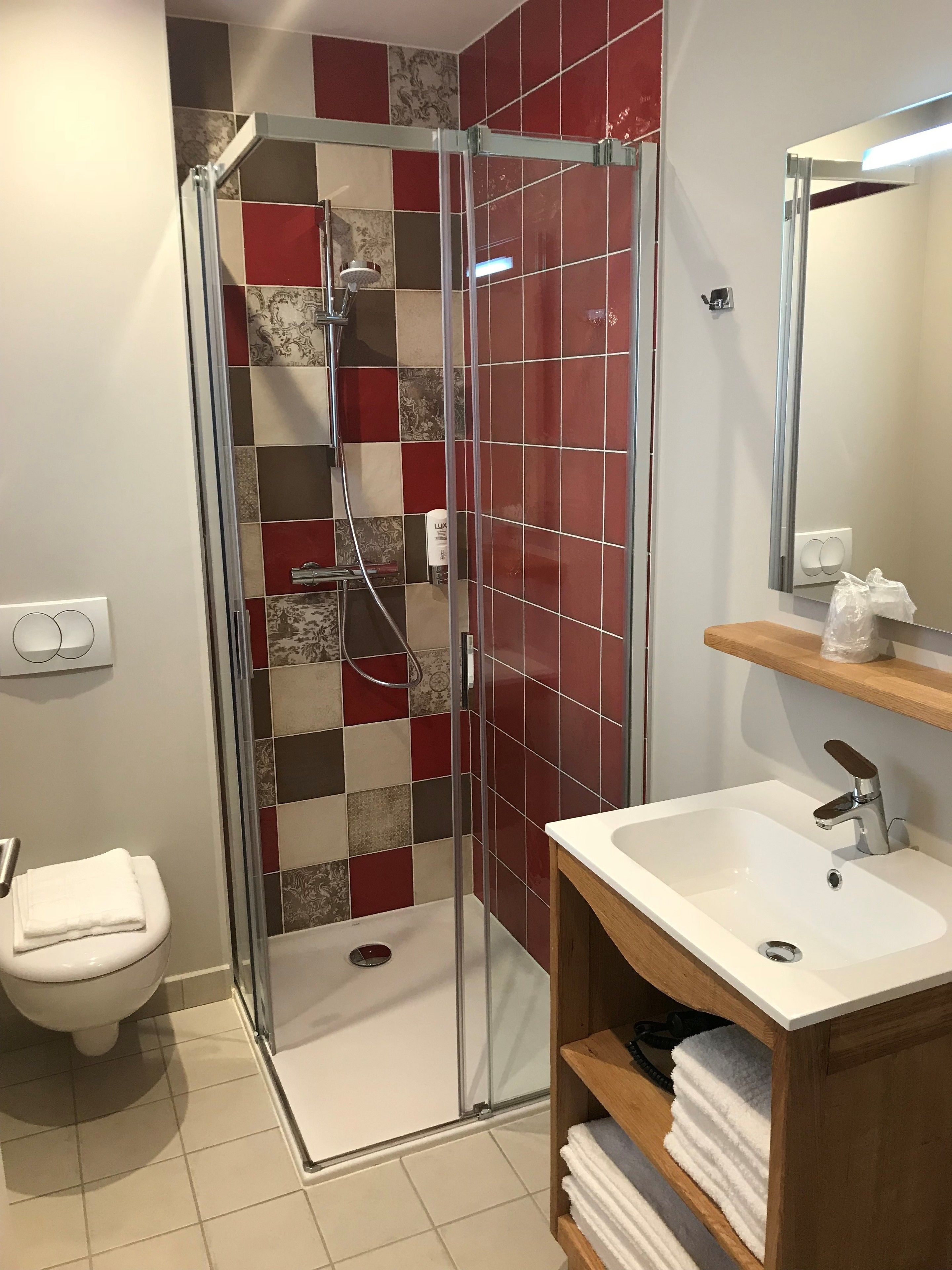 A bathroom with a glass-enclosed shower, a white sink, and a toilet.