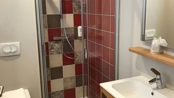 A bathroom with a glass-enclosed shower, a white sink, and a toilet.