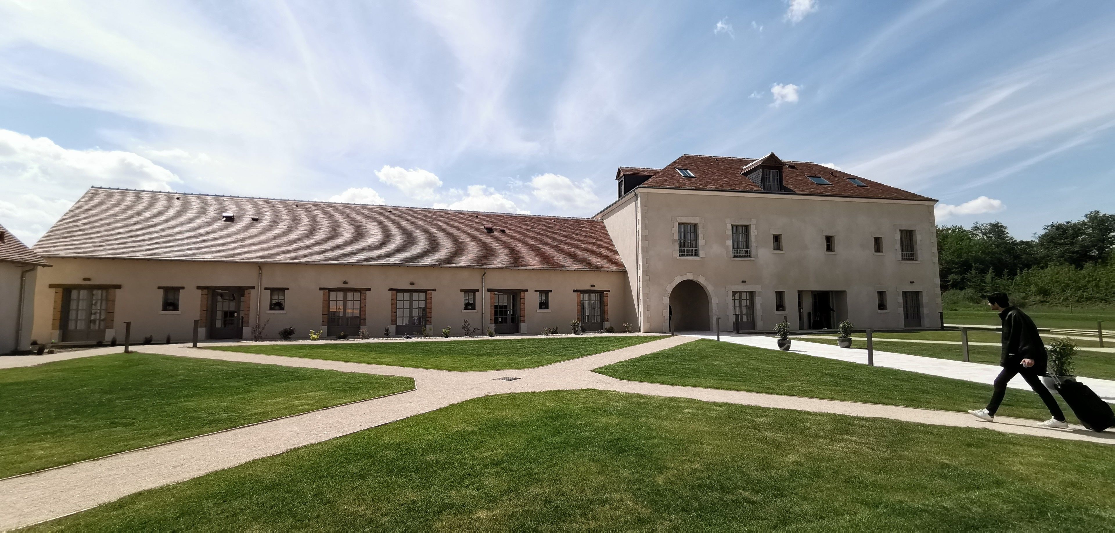 A courtyard with a building featuring a central archway and multiple windows.