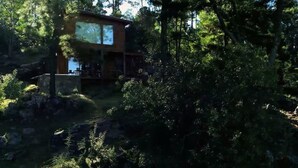 A modern house with a large deck, surrounded by dense forest. - Boschetto Suites De Bosques (Athos Pampa)