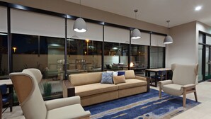 Un salon moderne avec un canapé, des fauteuils et des luminaires suspendus.