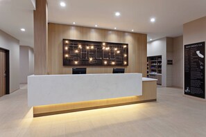 Een modern receptiebalie met een houten paneel als achtergrond en verlichte signage.