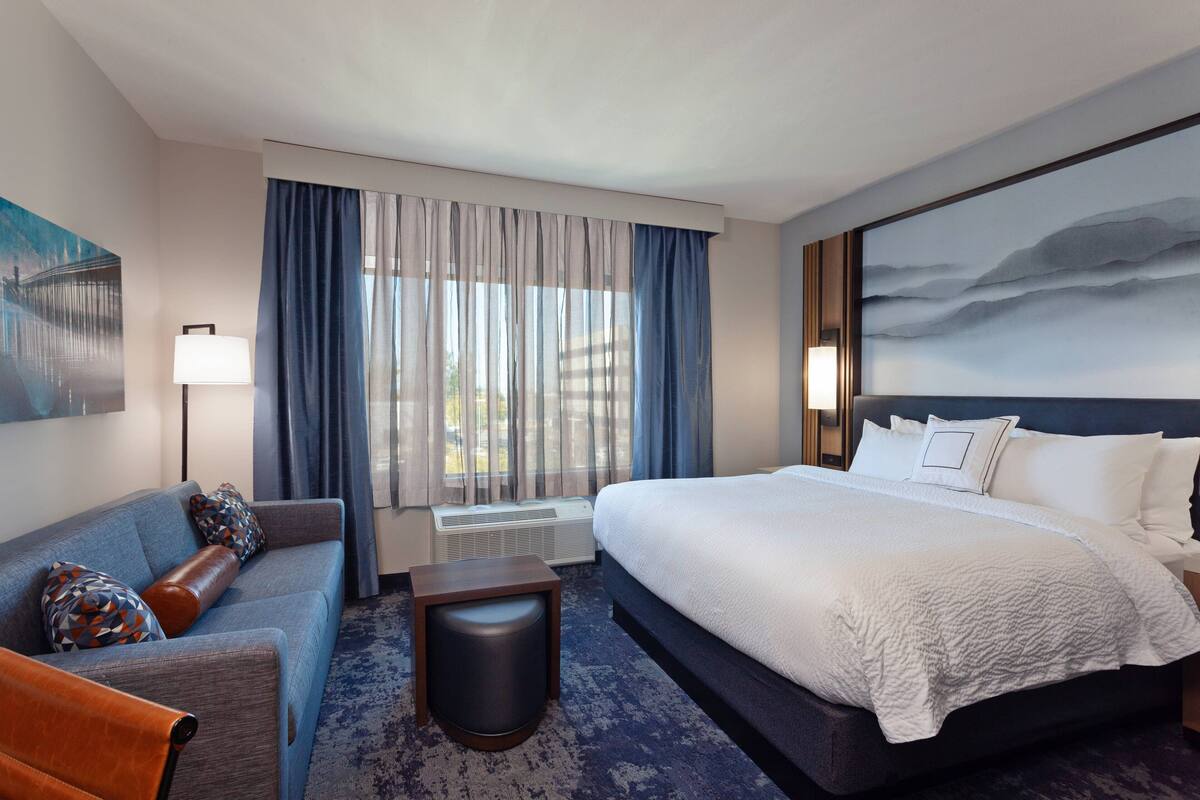 Une chambre d’hôtel avec un grand lit, un canapé, une petite table et un tableau au mur.