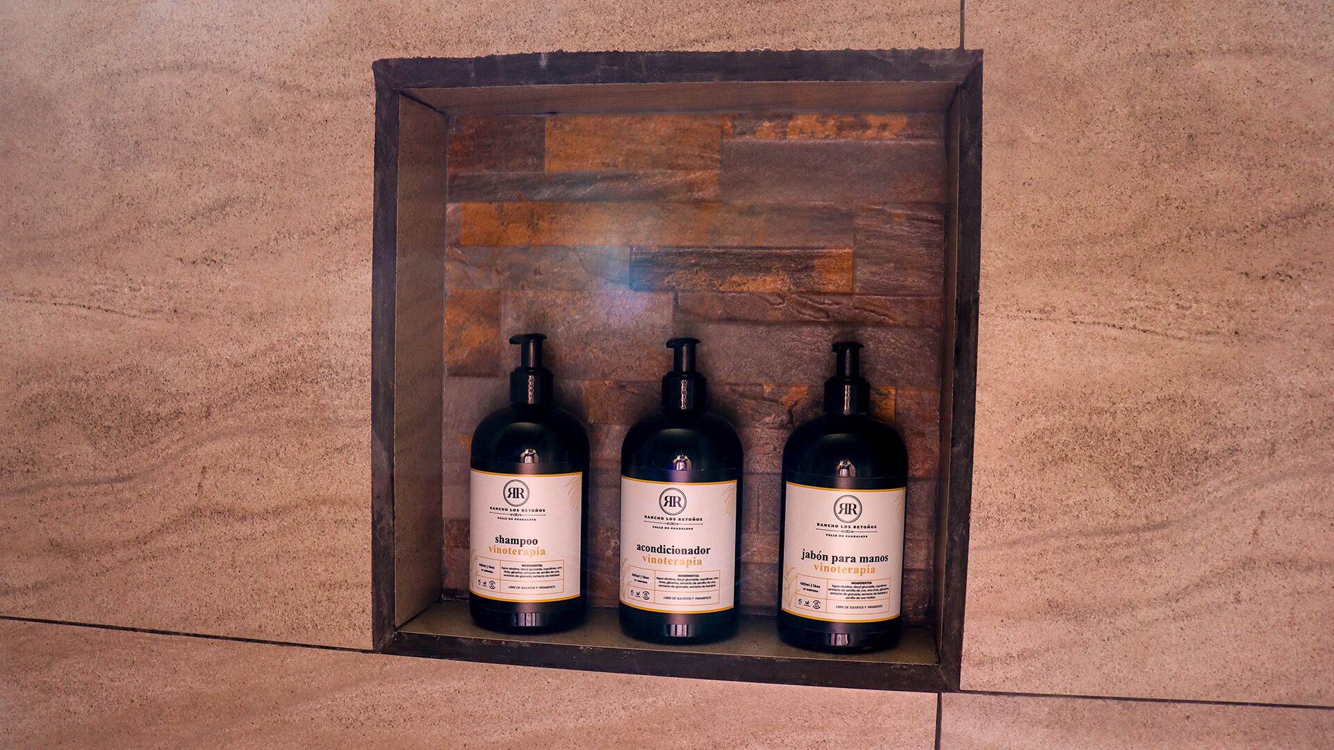 Three bottles of hair care products in a wooden display case.