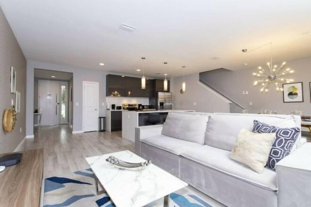 Una sala de estar moderna con un sofá, una mesa de centro y una escalera que lleva a una cocina.