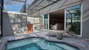 Ein moderner Poolbereich im Freien mit Whirlpool, einer Terrasse mit Sitzgelegenheiten und einem verglasten Wohnbereich.