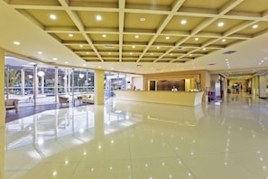 A spacious lobby with a reception desk, large windows, and a high ceiling with recessed lighting. - Hotel Kipriotis Village Resort (Kos)
