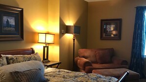 Quarto de hotel com uma cama grande, um sofá, um abajur e um ventilador de teto.