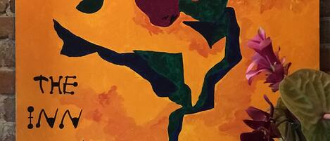 A painting of a stylized flower with text 'THE INN AT OPHELIA'S' on a brick wall background.