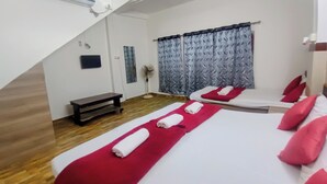 A hotel room with two beds, a bench, a standing fan, and a wall-mounted air conditioner. - Tourist Lodge (Haliyal)
