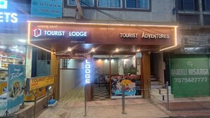 A Tourist Lodge with a sign indicating AC & Non AC rooms, a Travel Desk, and a Tourist Adventures sign. - Tourist Lodge (Haliyal)