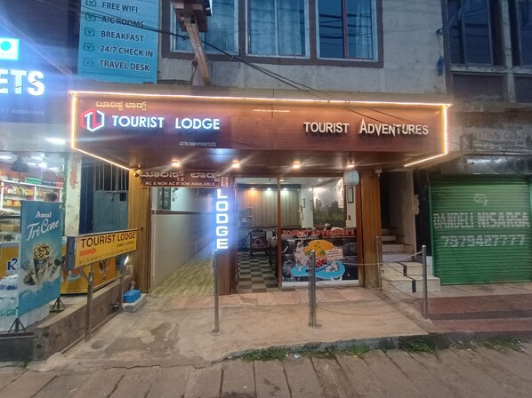 A Tourist Lodge with a sign indicating AC & Non AC rooms, a Travel Desk, and a Tourist Adventures sign.