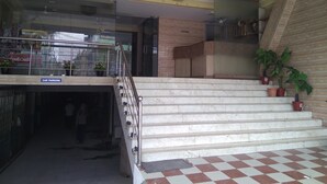 Entrada de un edificio con un letrero de estacionamiento para autos, escalones de mármol y plantas en macetas.