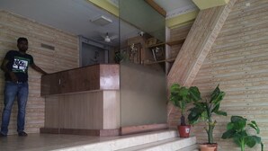 Una zona de recepción con mostrador de madera, escalones de mármol y plantas en macetas.