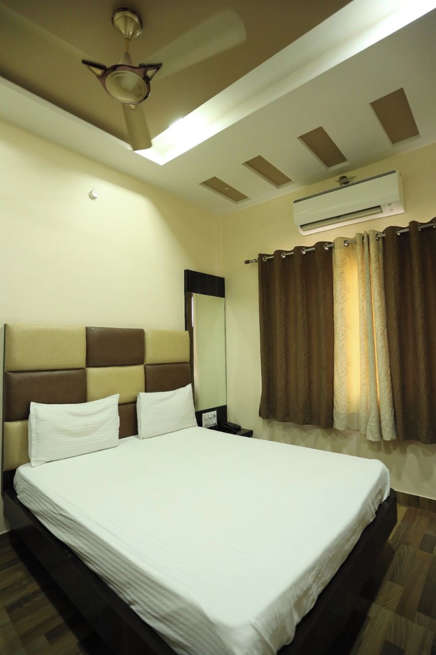 Ein Hotelzimmer mit einem großen Bett, einem Deckenventilator, einer Klimaanlage, einem Spiegel und Vorhängen.