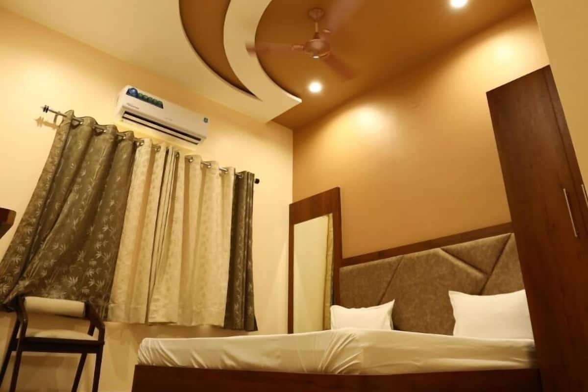 Ein Schlafzimmer mit einem Bett, einem Sessel, einer Klimaanlage und einem Deckenventilator.