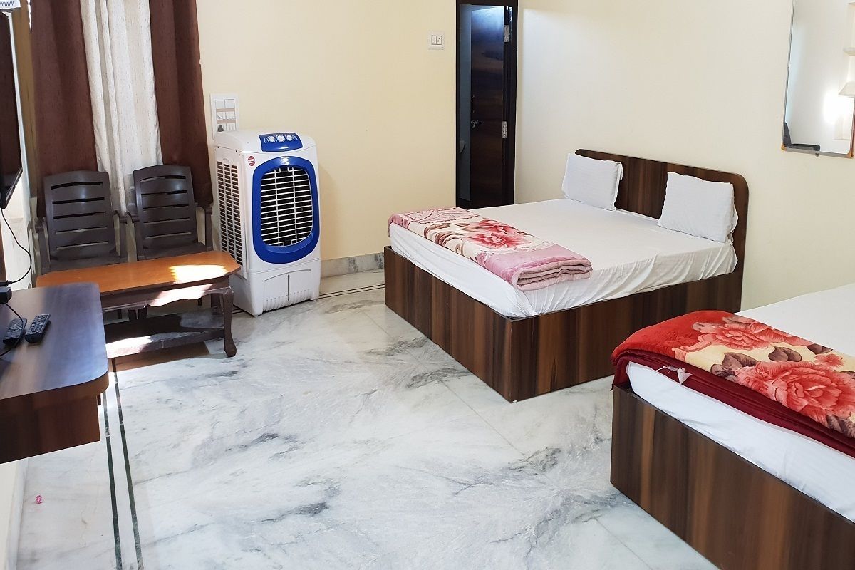 A hotel room with a bed, a desk, a chair, an air conditioner, and a wardrobe.