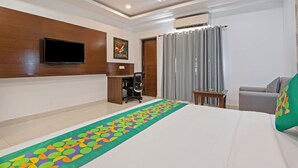 A hotel room with a bed, a desk, a chair, a television, and a window with curtains. - Treebo Premium Grand Legacy Elite with Roof Top Cafe (Dehradun)
