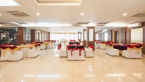 A spacious banquet hall with rows of tables and chairs, large windows, and a modern ceiling design. - Treebo Premium Grand Legacy Elite with Roof Top Cafe (Dehradun)