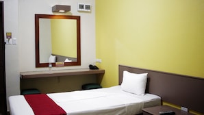 Une chambre d’hôtel équipée d’un lit, d’un bureau, d’un miroir et d’un téléphone.