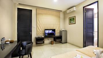 A hotel room with a bed, a desk with a chair, a television, and a minibar.