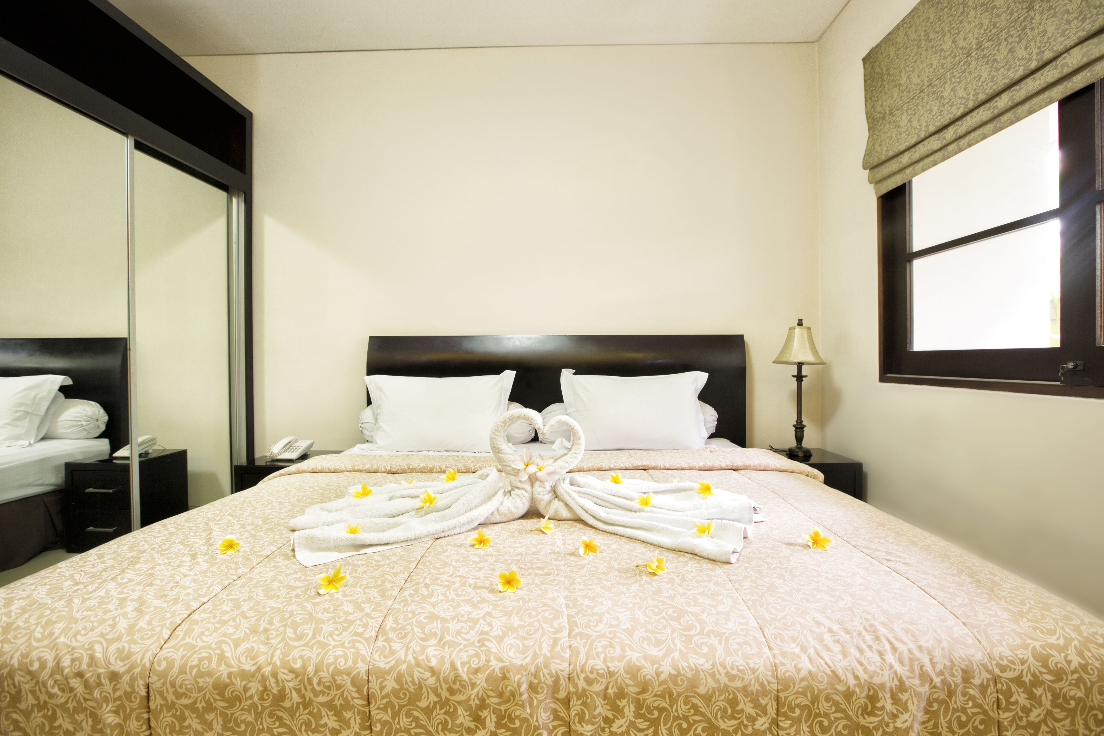 Una habitación de hotel con una cama grande, una mesita de noche con lámpara y un espejo en la pared.