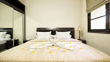 Una habitación de hotel con una cama grande, una mesita de noche con lámpara y un espejo en la pared.