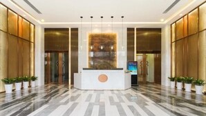 A modern reception area with a marble floor, a central reception desk, and potted plants. - Zhuhai Boruiwan Binjiang Hotel (Zhuhai)