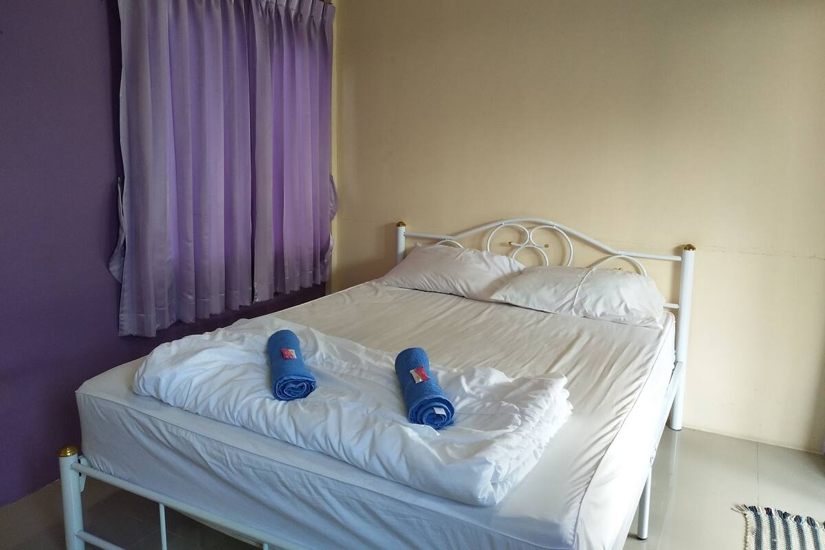 A bed with white bedding and two rolled towels on it.