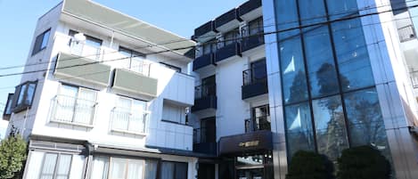 Un hotel moderno con fachada de vidrio, varios balcones y una entrada visible.