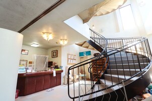 A spiral staircase with a metal railing, a reception desk with a counter, and a bulletin board with notices.