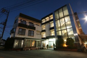 A multi-story hotel with balconies, large windows, and a well-lit entrance.