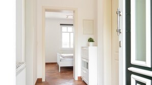 A hallway with a white radiator, a white door, and a white cabinet with drawers.