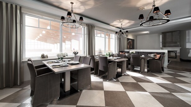 A modern dining area with a checkered floor, large windows, and contemporary chandeliers.