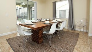 Un espace repas moderne avec une table en bois, des chaises blanches et un tapis à motifs.