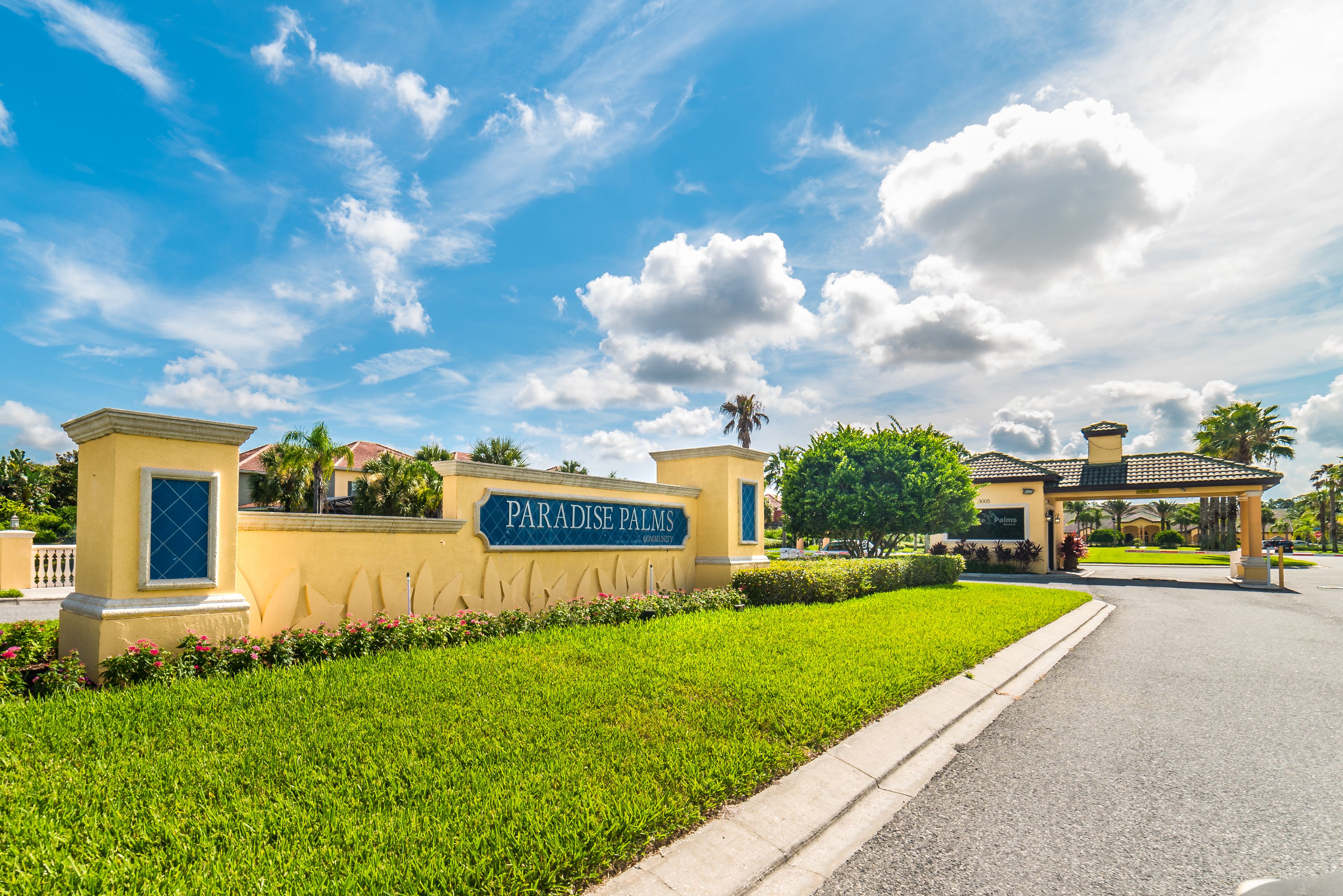 A well-maintained entrance with a sign reading "Paradise Palms" and a clear pathway leading to the building.