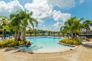 Uma grande piscina ao ar livre rodeada por palmeiras e espreguiçadeiras.