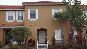 A two-story building with a beige facade, white shutters, and a red-tiled roof. - Ov3696 - Terra Verde Resort - 3 Bed 2.5 Baths Townhome (Kissimmee)