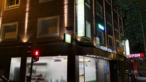 A multi-story building with illuminated signage, including a restaurant named "Golden Alhambra" and a store named "CEPSA". - Hostal Golden Alcalá (Madrid)