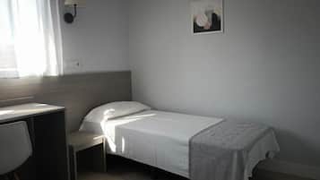 Un dormitorio pequeño y ordenado con una cama individual, un escritorio y una silla.
