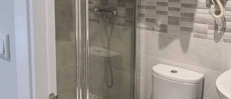 Un baño moderno con ducha de vidrio, inodoro y lavamanos.