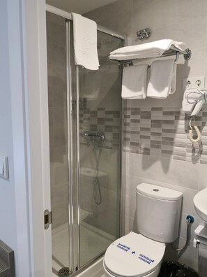 Un bany modern amb dutxa tancada per vidre, un vàter i un lavabo.