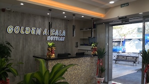 A hotel reception area with a modern design, including a reception desk, potted plants, and a sign reading "GOLDEN ALCALA HOTELES". - Hostal Golden Alcalá (Madrid)