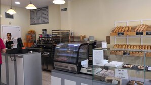 A bakery counter with various baked goods displayed, a menu board, and a cash register. - Hostal Golden Alcalá (Madrid)
