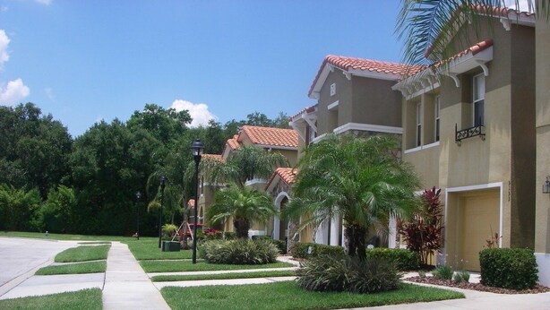 A residential area with a row of two-story houses, each with a red-tiled roof and beige walls.