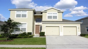 A two-story house with a garage, a front door, and a small front yard with a tree and shrubs. - Ov3649 - Windsor Hills Resort - 5 Bed 5 Baths Villa (Kissimmee)