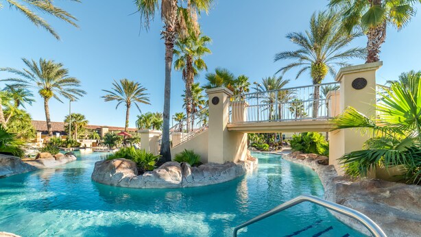 A swimming pool with clear blue water, surrounded by palm trees and rocks, and a bridge over the pool. - Ov3637 - Regal Palms Resort & Spa - 4 Bed 3.5 Baths Villa (Davenport)